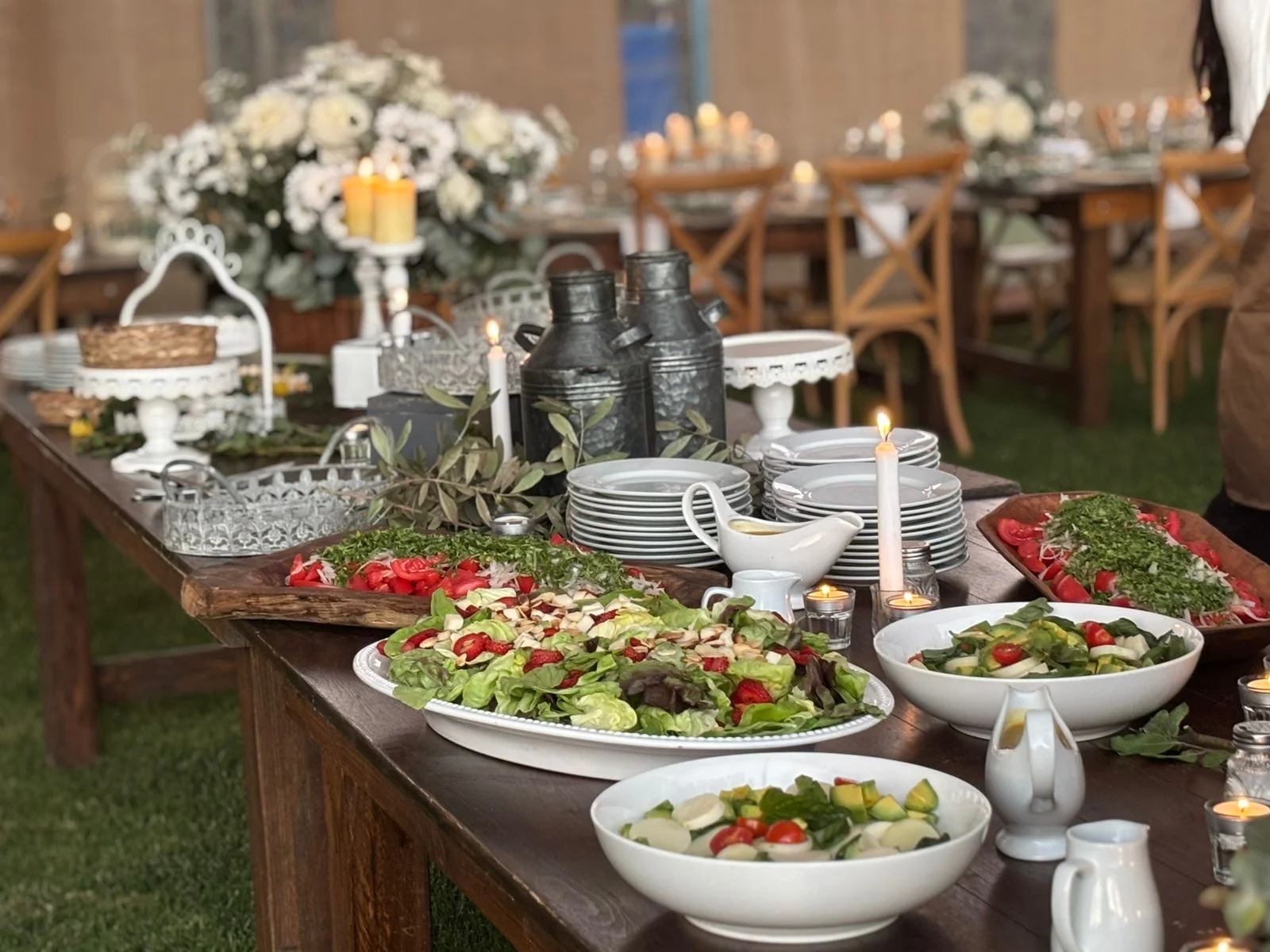 Mesa buffet de ensaladas frescas con lecheros de zinc, centros florales y velas en un banquete de matrimonio de Matías al Fuego